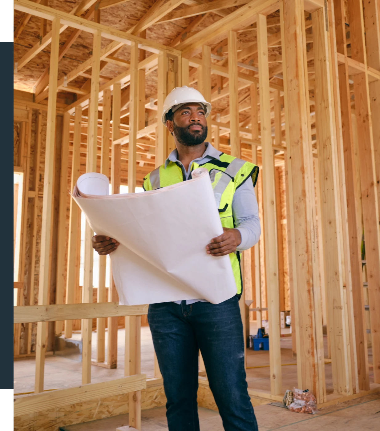 Construction worker holding building plans indoors.