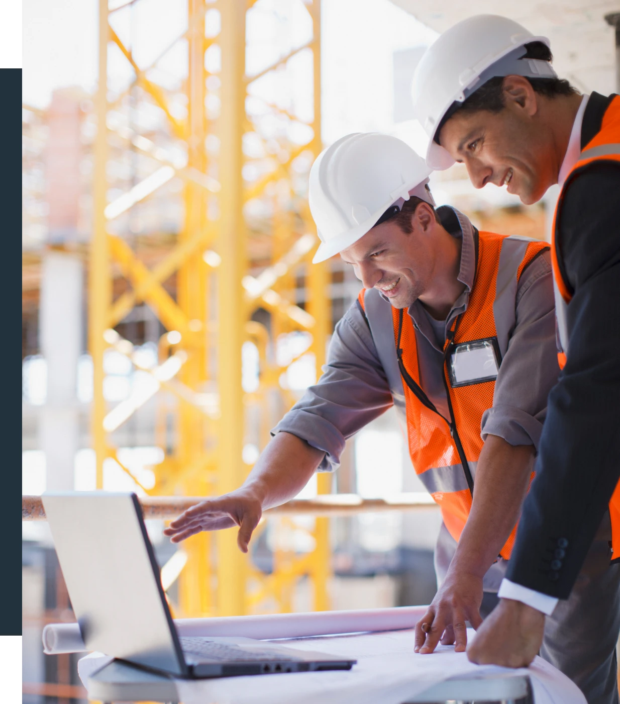 Construction workers reviewing plans on laptop.